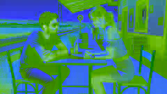 Una mujer se levanta de una mesa en una estación de tren rural en España, mientras que el hombre permanece sentado, luciendo incómodo.