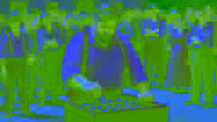 Herr Summers rührt die Papiere in der schwarzen Holzbox um, während die Dorfbewohner nervös im Hintergrund zusammenkommen.