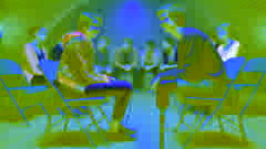 Hazel and Augustus meet for the first time in a cancer support group, surrounded by other teens in a dimly lit room.